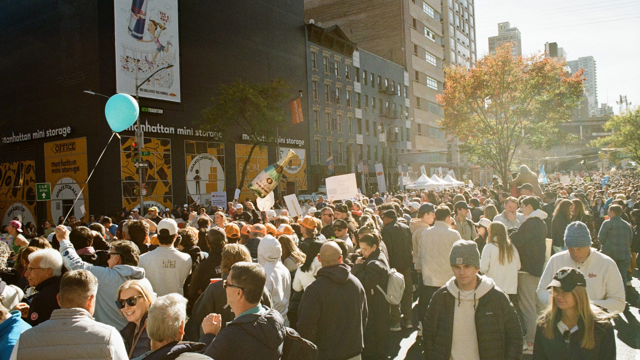 Dense crowd at the 2024 NYC Marathon with a single teal balloon visible above the sea of faces